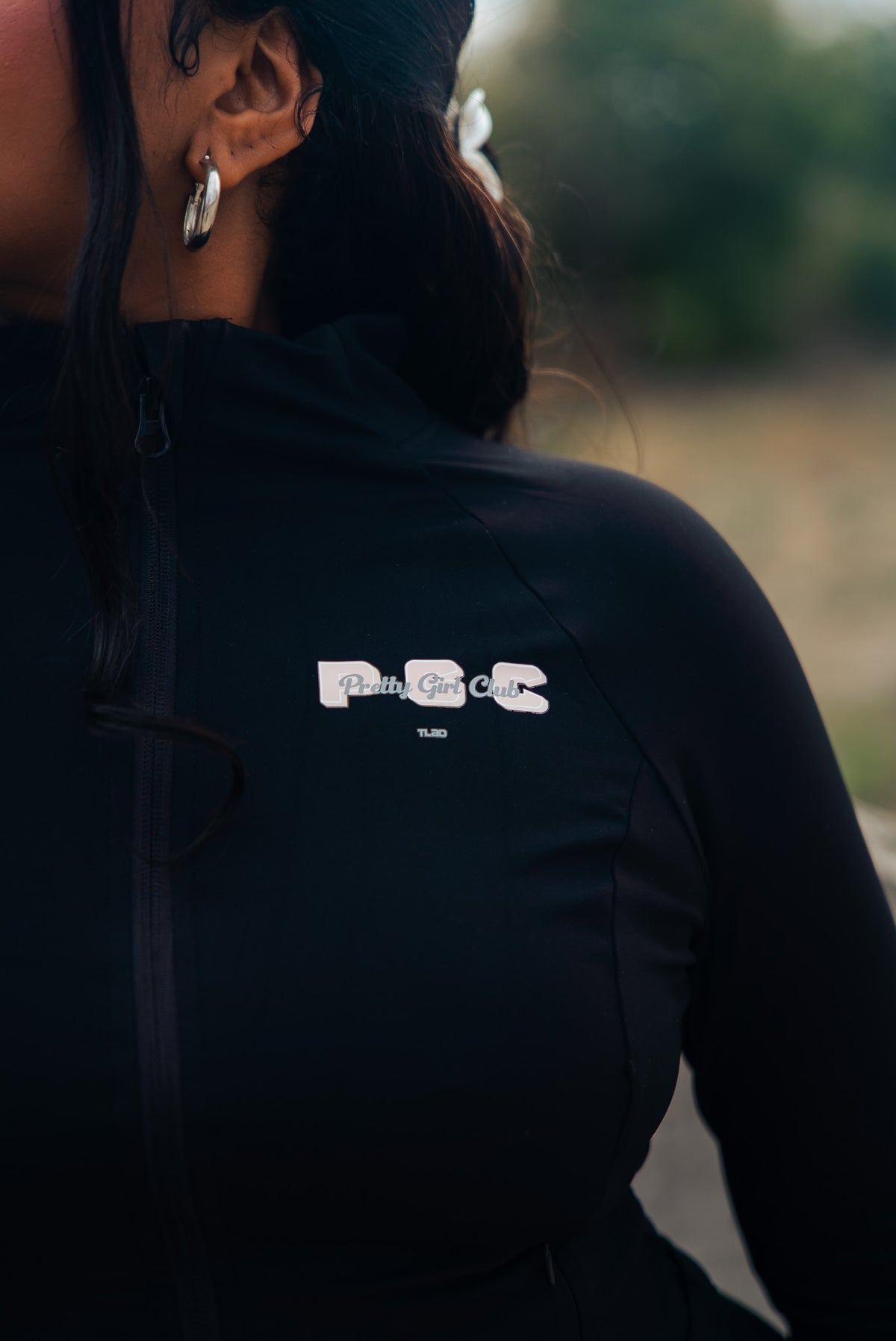 Close up of Pretty Girl Club black fitted lounge jacket with pink PGC chest logo